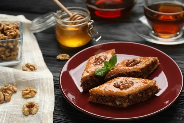 Cevizli ve nane şekerli lezzetli baklava siyah ahşap masa, yakın plan.
