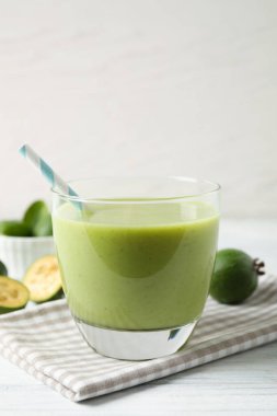 Beyaz ahşap masada cam içinde taze feijoa smoothie, yakın plan.