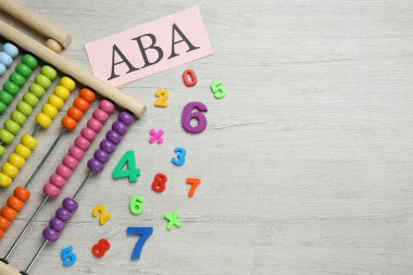 ABA (Uygulamalı Davranış Analizi), Abaküs ve beyaz ahşap masa üzerindeki renkli sayılar, düz yatış. Metin için boşluk