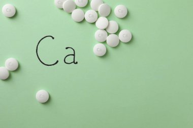 Açık yeşil zemin üzerinde kalsiyum takviye hapları ile düz konum, metin için boşluk