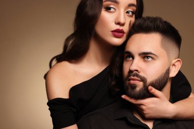 Açık kahverengi arka planda seksi bayan olan yakışıklı sakallı adam.