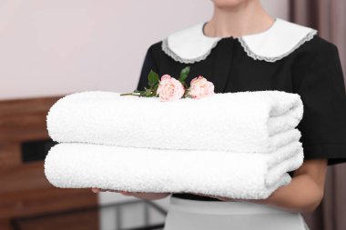 Otel odasında temiz havlu yığını olan oda hizmetçisi, yakın plan.