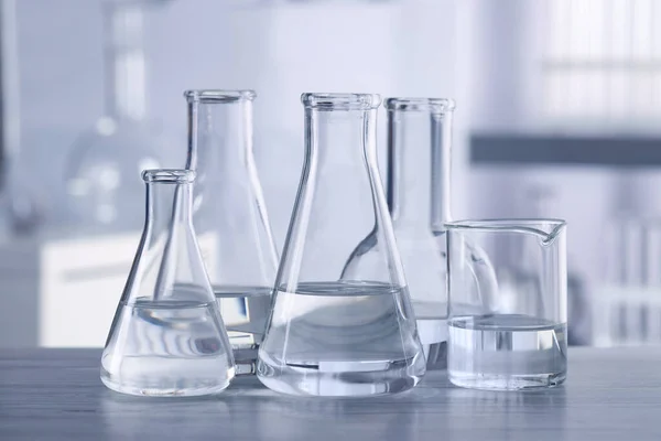 Different Laboratory Glassware Transparent Liquid Wooden Table Blurred Background — Stock Photo, Image