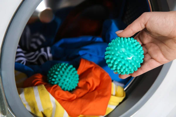 洗濯機に緑色のドライヤーボールを入れて閉じる女性 — ストック写真