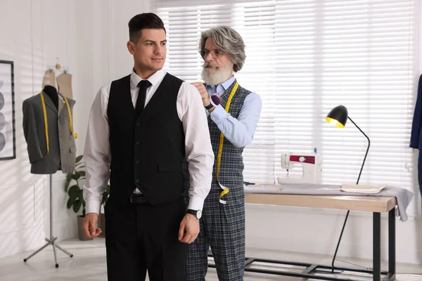 Atölyede müşteriyle çalışan profesyonel terzi