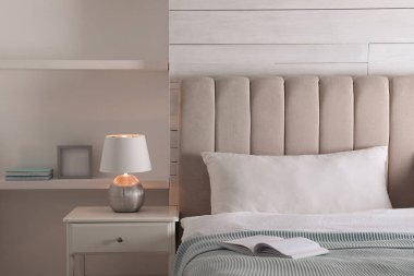 Yatak odasındaki komodinin üzerinde şık bir gece lambası.