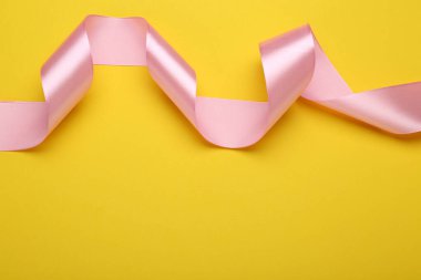 Sarı arka planda güzel pembe kurdele, üst manzara. Metin için boşluk
