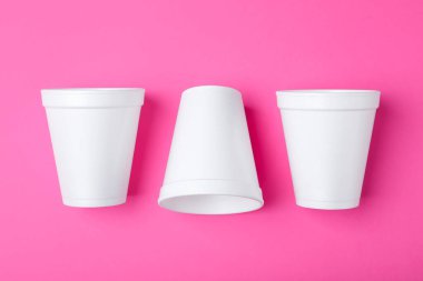 Pembe arka planda beyaz köpük bardaklar, düz uzanmış.