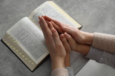 Oğlan ve vaftiz ebeveyni gri masada birlikte dua ediyor. Yakın plan.