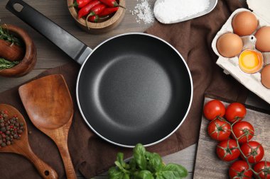 Düz kompozisyon, mutfak aletleri, kızartma tavası ve ahşap masa üzerine taze malzemeler.