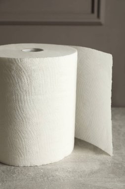 Gri masa üzerinde beyaz kağıt havlu rulosu