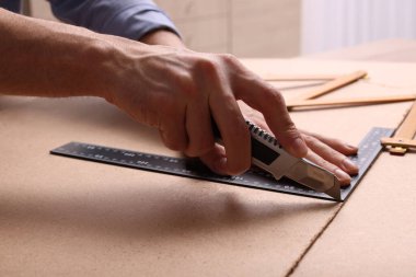 Fiş tahtasını bıçak ve cetvelle kesen adam, yakın plan.