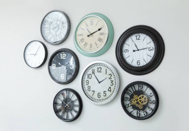 Beyaz duvarda asılı bir sürü farklı saat.