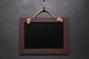 Siyah duvarda asılı küçük, temiz bir karatahta.