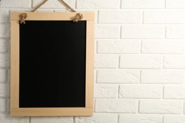 Beyaz tuğla duvarda asılı temiz, küçük siyah karatahta, metin için boşluk