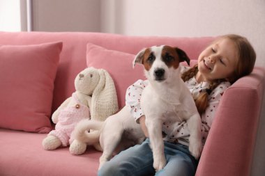 Kanepesinde köpeği olan sevimli küçük bir kız, mesaj atmak için yer var. Çocukluk hayvanı.