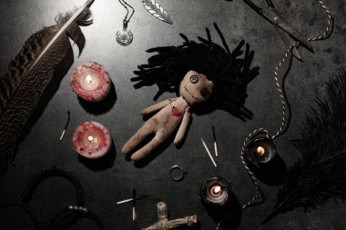 Kalbi iğneli kadın voodoo bebeği ve gri masada tören eşyaları, düz yatıyordu.
