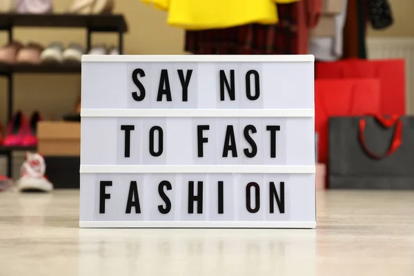 Lightbox with phrase SAY NO TO FAST FASHION on floor indoors