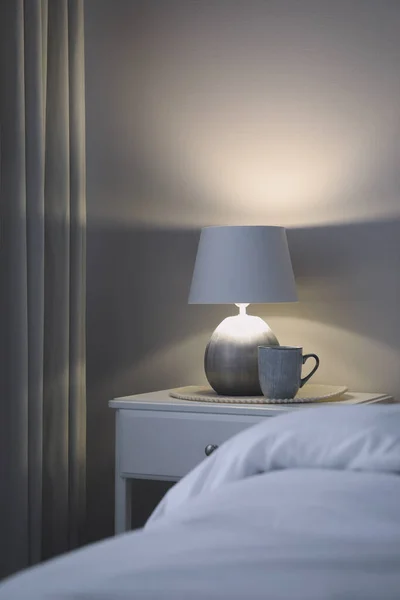 침실에 나이트 스탠드 위에서 아름다운 램프와 한잔의 — 스톡 사진