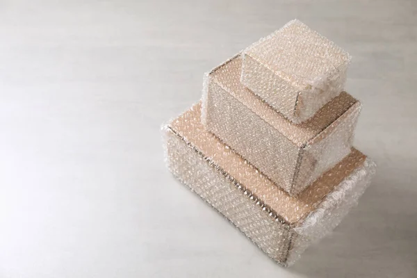 Caixas Papelão Cobertas Com Plástico Bolha Mesa Cinza Claro Espaço — Fotografia de Stock
