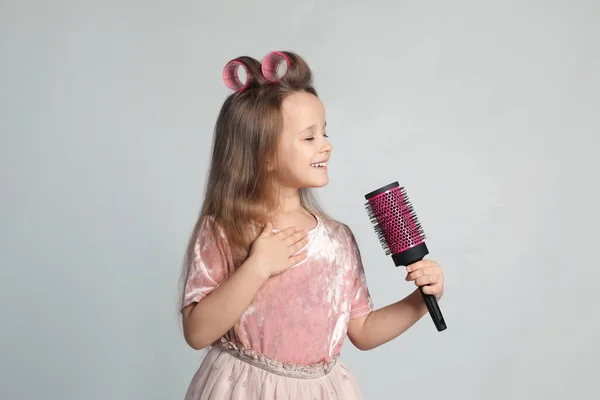 Açık Gri Arka Planda Saç Fırçasıyla Şarkı Söyleyen Sevimli Küçük — Stok fotoğraf