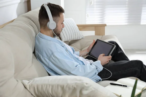 Mladý Muž Sluchátky Používající Moderní Tablet Studiu Pohovce Doma Vzdálené — Stock fotografie