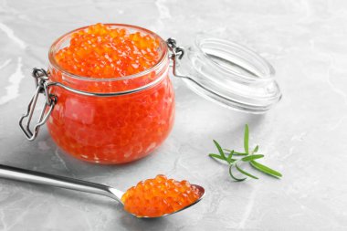 Açık gri masada lezzetli kırmızı havyar ve biberiye.