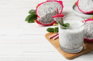 Bir bardak lezzetli pitahaya smoothie beyaz ahşap masa üzerinde taze nane ile, metin için yer
