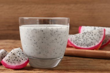 Bir bardak lezzetli pitahaya smoothie ve ahşap masada taze meyve, metin için yer var.