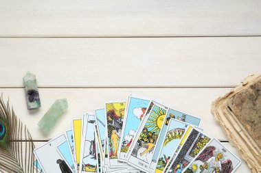 Tarot kartları, eski kitaplar, kristaller ve tavus kuşu tüyü beyaz ahşap masa üzerinde, düz yatıyordu. Metin için boşluk
