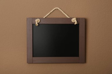 Kahverengi duvarda asılı küçük, temiz bir kara tahta.