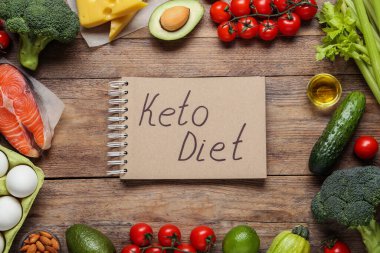 Keto Diyet cümleli defter ve ahşap masa üzerinde farklı ürünler, düz yatıyordu