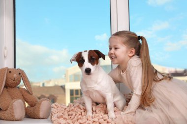 Köpeği pencere eşiğinde oturan sevimli küçük bir kız. Mesaj atmak için uygun bir yer. Çocukluk hayvanı.