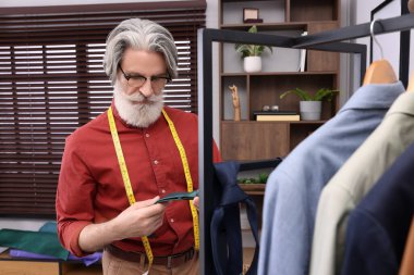 Atölyenin yanında yeşil kravatlı profesyonel bir terzi.