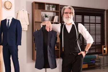 Atölyede manken yakınında mezurası olan profesyonel bir terzi.