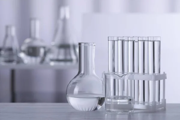 Different Laboratory Glassware Transparent Liquid Wooden Table Blurred Background Space — Zdjęcie stockowe