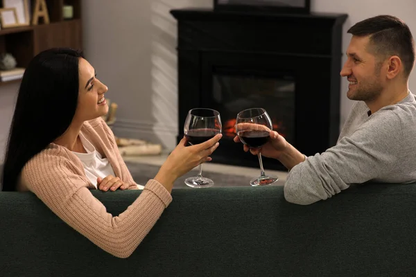 可爱的情侣们 带着酒杯 在家里壁炉边的沙发上共度时光 — 图库照片