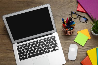 Modern dizüstü bilgisayar, gözlük ve ofis kâğıtları ahşap masada, düz yerde. Uzaklık öğrenimi