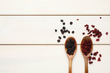 Kurutulmuş kırmızı ve siyah frenk üzümü beyaz ahşap masada, düz yerde. Metin için boşluk