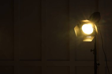 Karanlık odada, duvarın yanında parlak sarı spot ışığı, metin için boşluk