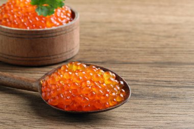 Tahta masada lezzetli kırmızı havyarlı kaşık ve kase, yakın plan. Metin için boşluk