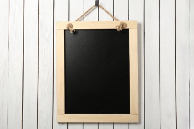 Beyaz ahşap duvarda asılı temiz, küçük siyah bir karatahta.