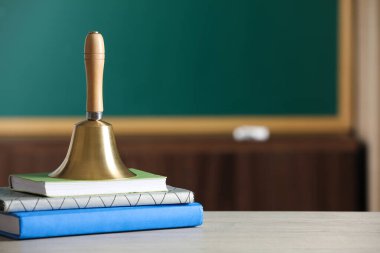 Altın okul zili ve kitaplar sınıftaki ahşap masa, metin için yer