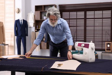 Atölyedeki masada mezurası olan profesyonel bir terzi.