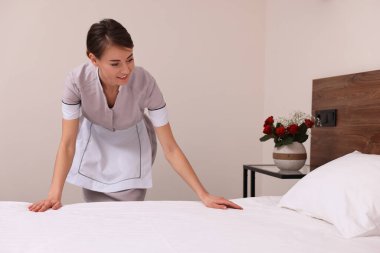 Otel odasında yatak yapan güzel oda hizmetçisi.