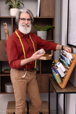 Atölyenin yanında iplik seçen profesyonel bir terzi