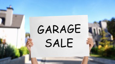 Elinde GARAGE satışı yazılı tabela olan kadın, yakın plan.