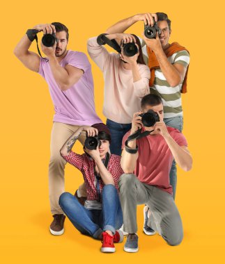 Turuncu arka planda kameraları olan bir grup profesyonel fotoğrafçı