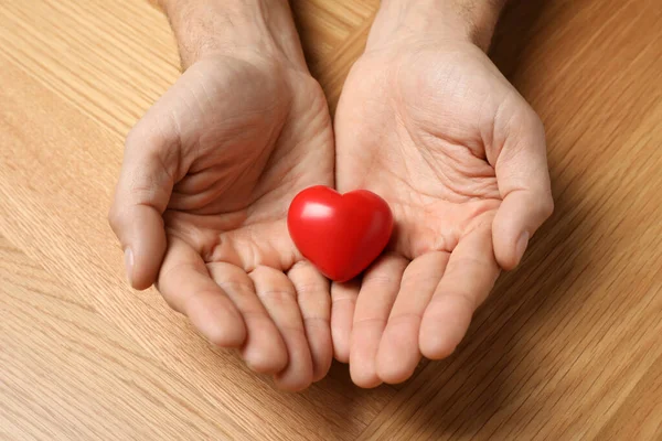 Man Holding Red Heart Hands Wooden Table Closeup — стоковое фото