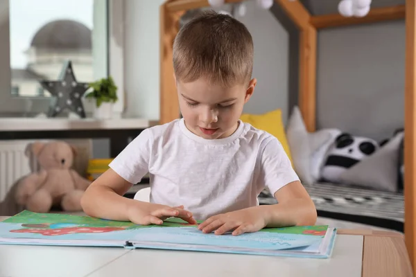 Cute Little Boy Reading Book Table Room — Foto de Stock